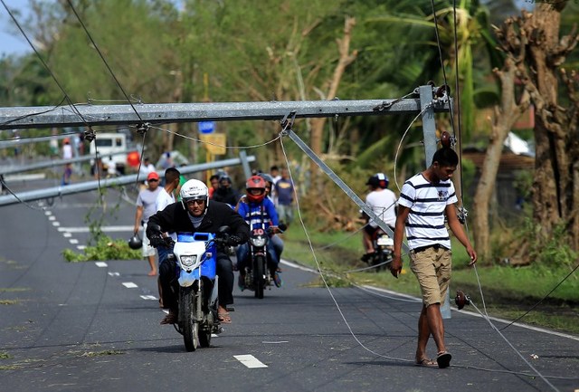 Motorists drive past downed electric posts on the national road after typhoon Nock-Ten made landfall in Nabua, Camarines Sur on December 26, 2016. Typhoon Nock-Ten, which made landfall on the eastern island province of Catanduanes on December 25, is forecast to move westward towards the country's heartland, packing winds of 215 kilometres (134 miles) per hour. / AFP PHOTO / CHARISM SAYAT