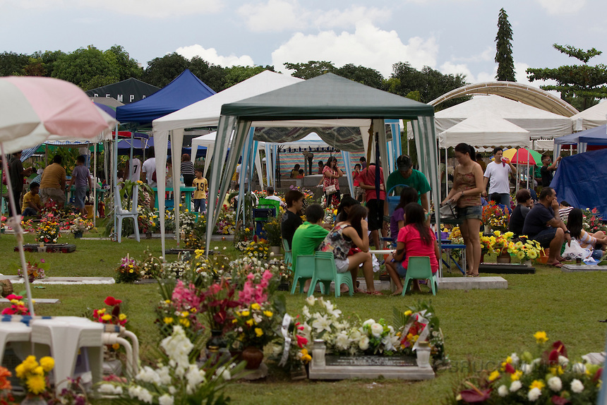 A family gathering around the grave of a loved one is the traditional way of remembrance in this private cmemetery, Saint Park;Cebu City;Philippines